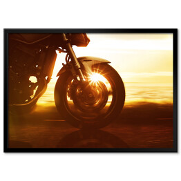 Plakat w ramie Koło motocyklu na tle złocistego zachodu słońca