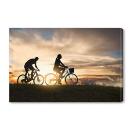 Obraz na płótnie Młoda para jadąca rowerami o zachodzie słońca