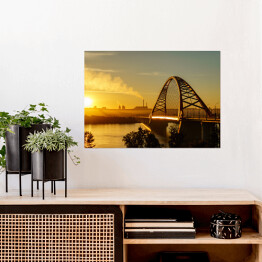 Plakat Most nad rzeką w mieście ze spektakularnym wschodem słońca w tle
