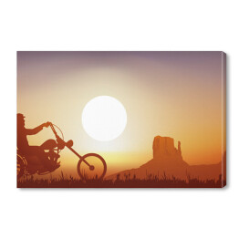 Obraz na płótnie Motocyklista na tle zachodu słońca w pomarańczowym i niebieskim odcieniu